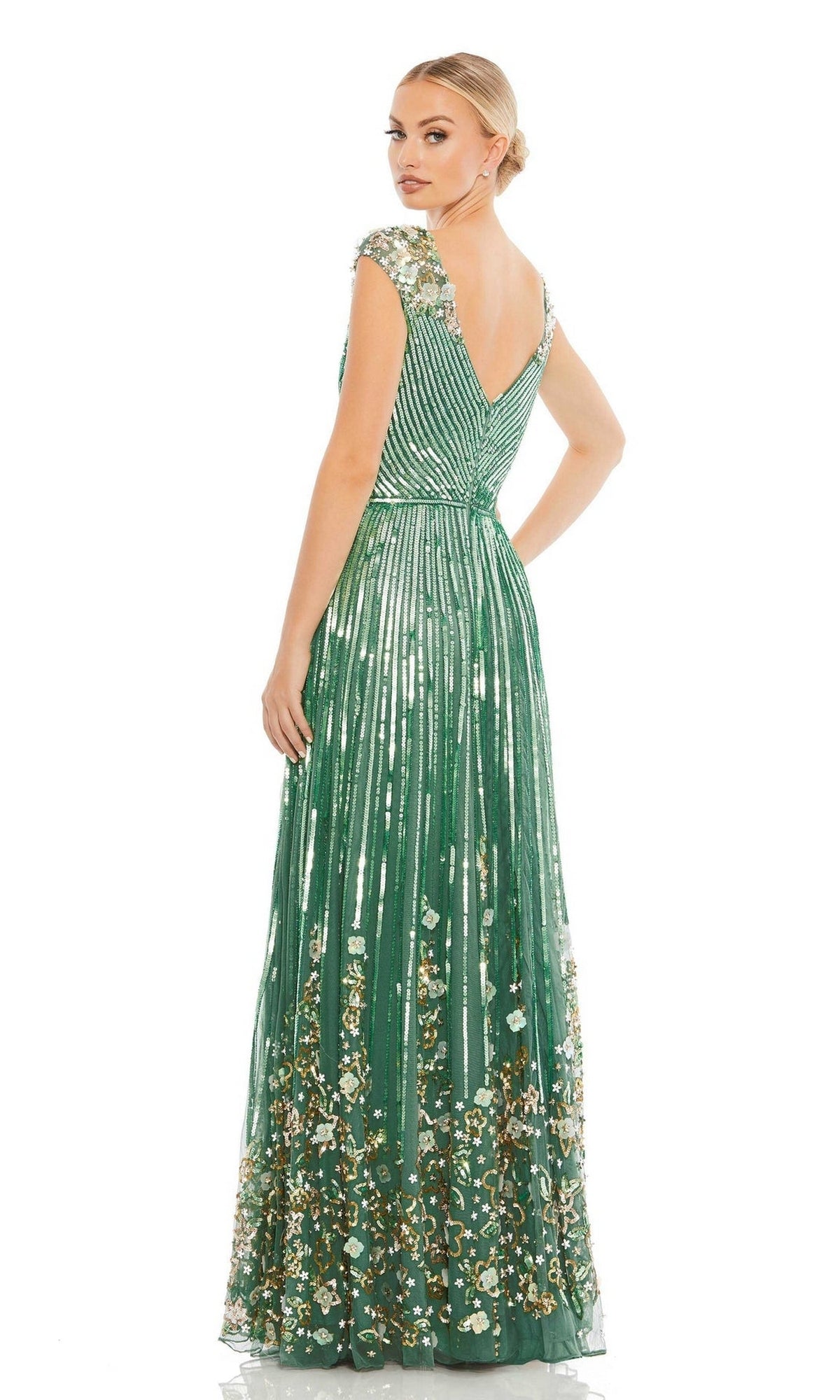 A woman wearing the Long Formal Dress 5223 by Mac Duggal, a sage green sequin A-line gown with floral embellishments and beaded cap sleeves, faces backward and looks over her shoulder.